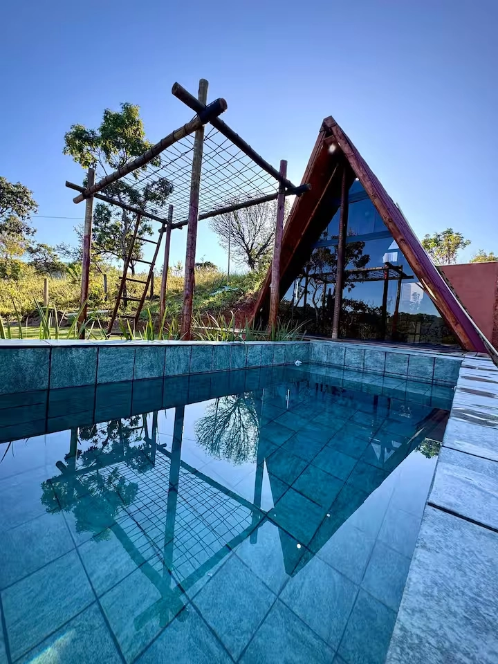 Piscina privativa cristalina com reflexo do chalé